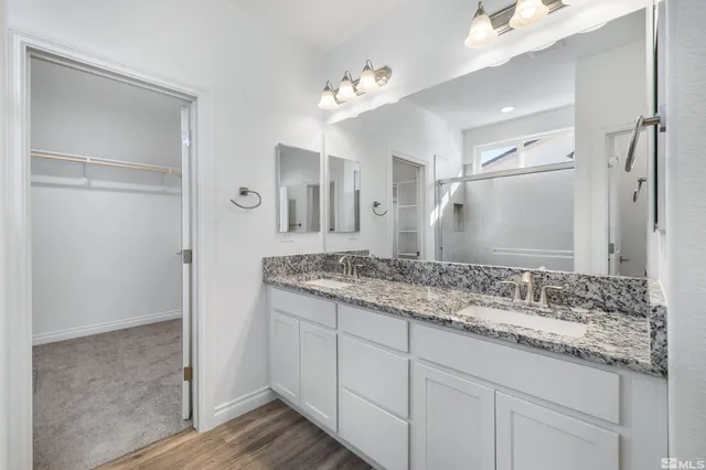 a bathroom with a granite countertop sink a mirror and a shower