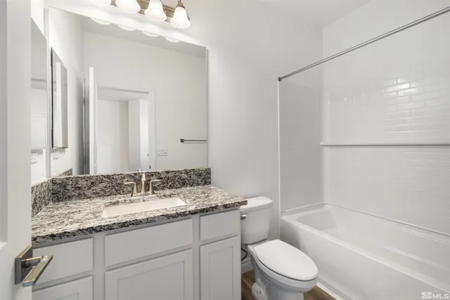 a bathroom with a granite countertop sink a toilet and shower