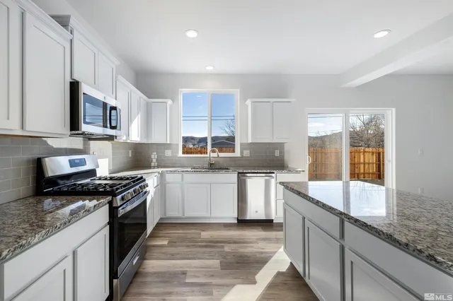 a kitchen with stainless steel appliances granite countertop a sink stove and cabinets