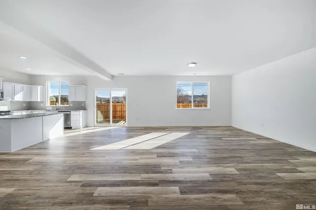 a view of an empty room with kitchen and window