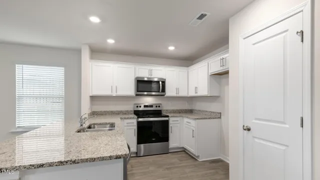 a kitchen with stainless steel appliances granite countertop a stove a sink and a refrigerator