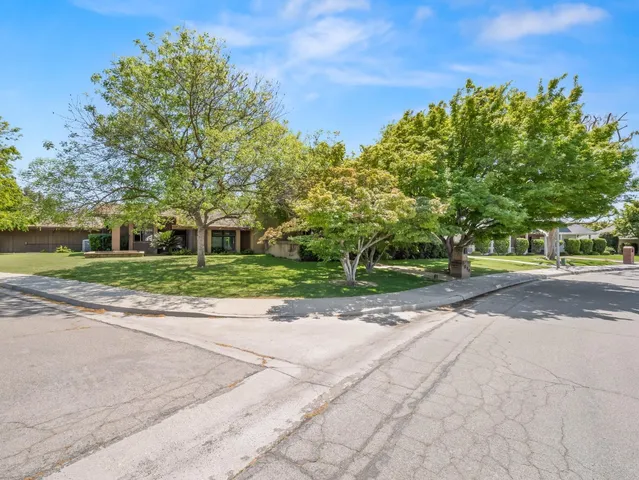 a view of a house with a big yard plants and large trees