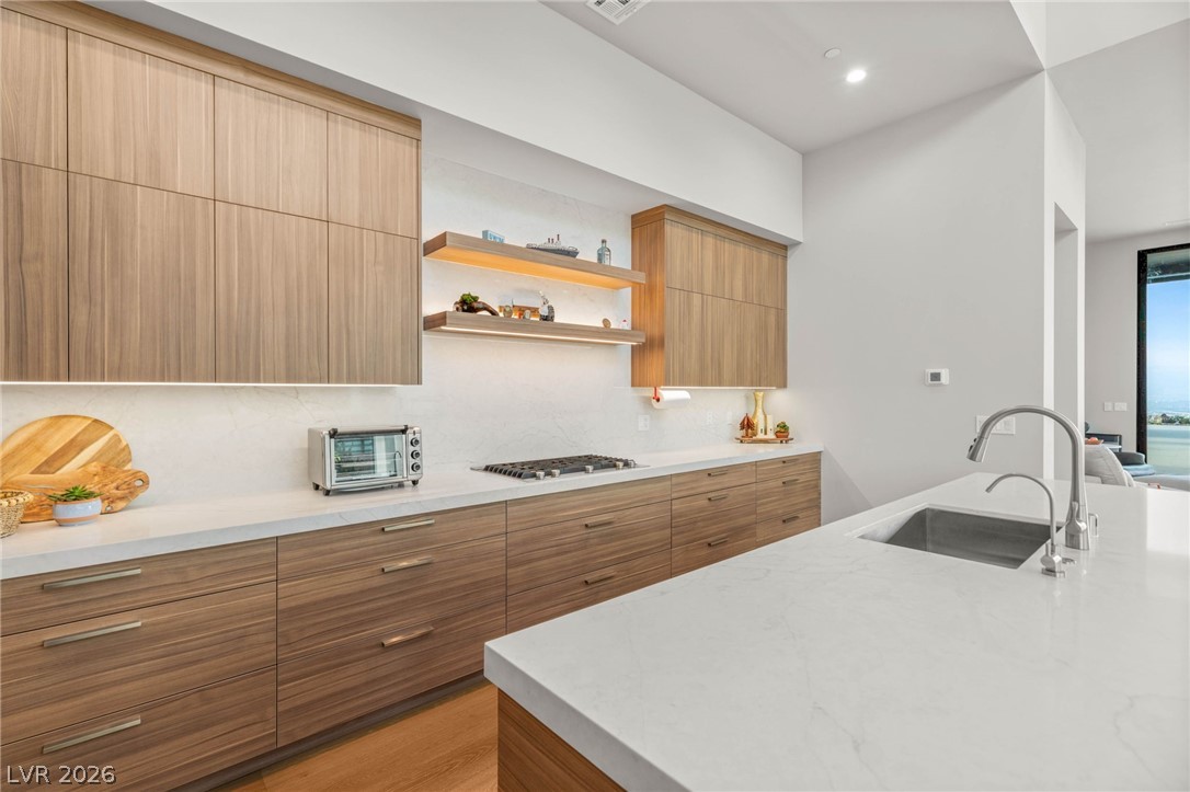 571 Overlook Rim Drive Henderson, NV 89012 - Photo 12 of 85 Kitchen with modern cabinets, open shelves, light stone counters, backsplash, and recessed lighting
