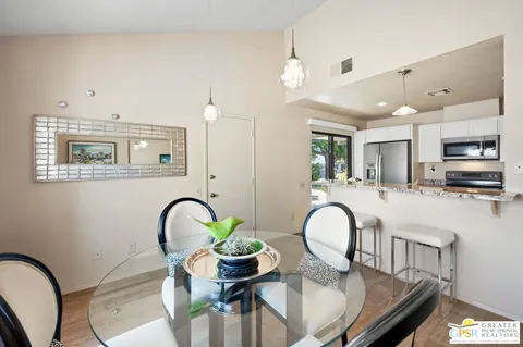 a kitchen with stainless steel appliances granite countertop a dining table chairs refrigerator and sink