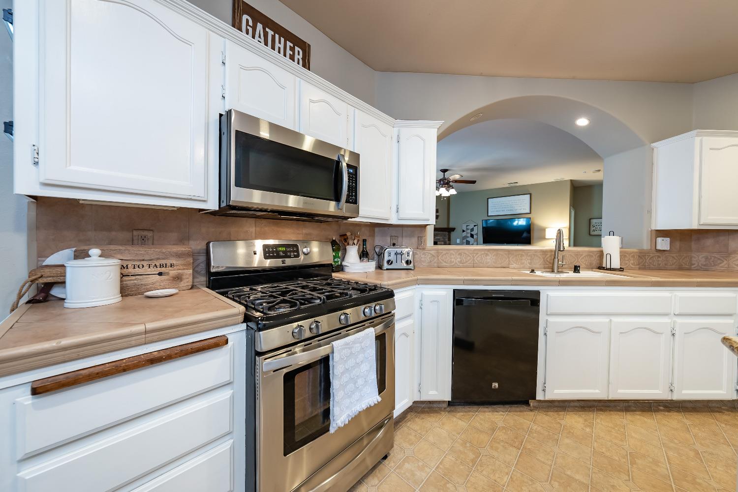 696 Crescent Lane Lemoore, CA 93245 - Photo 12 of 35 a kitchen with stainless steel appliances granite countertop a stove top oven a sink dishwasher and white cabinets