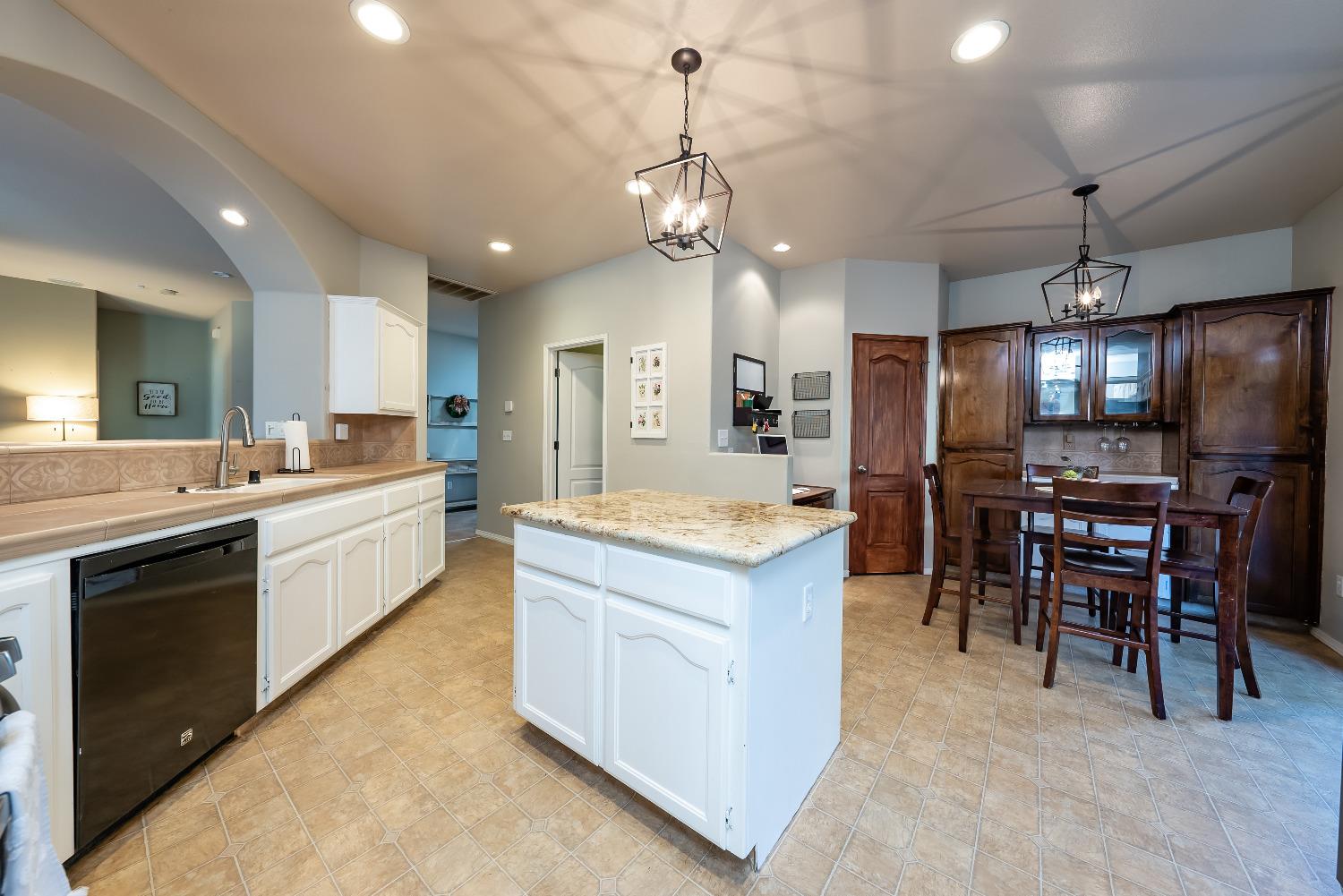 696 Crescent Lane Lemoore, CA 93245 - Photo 13 of 35 a large kitchen with kitchen island a refrigerator a stove a sink a dining table and chairs