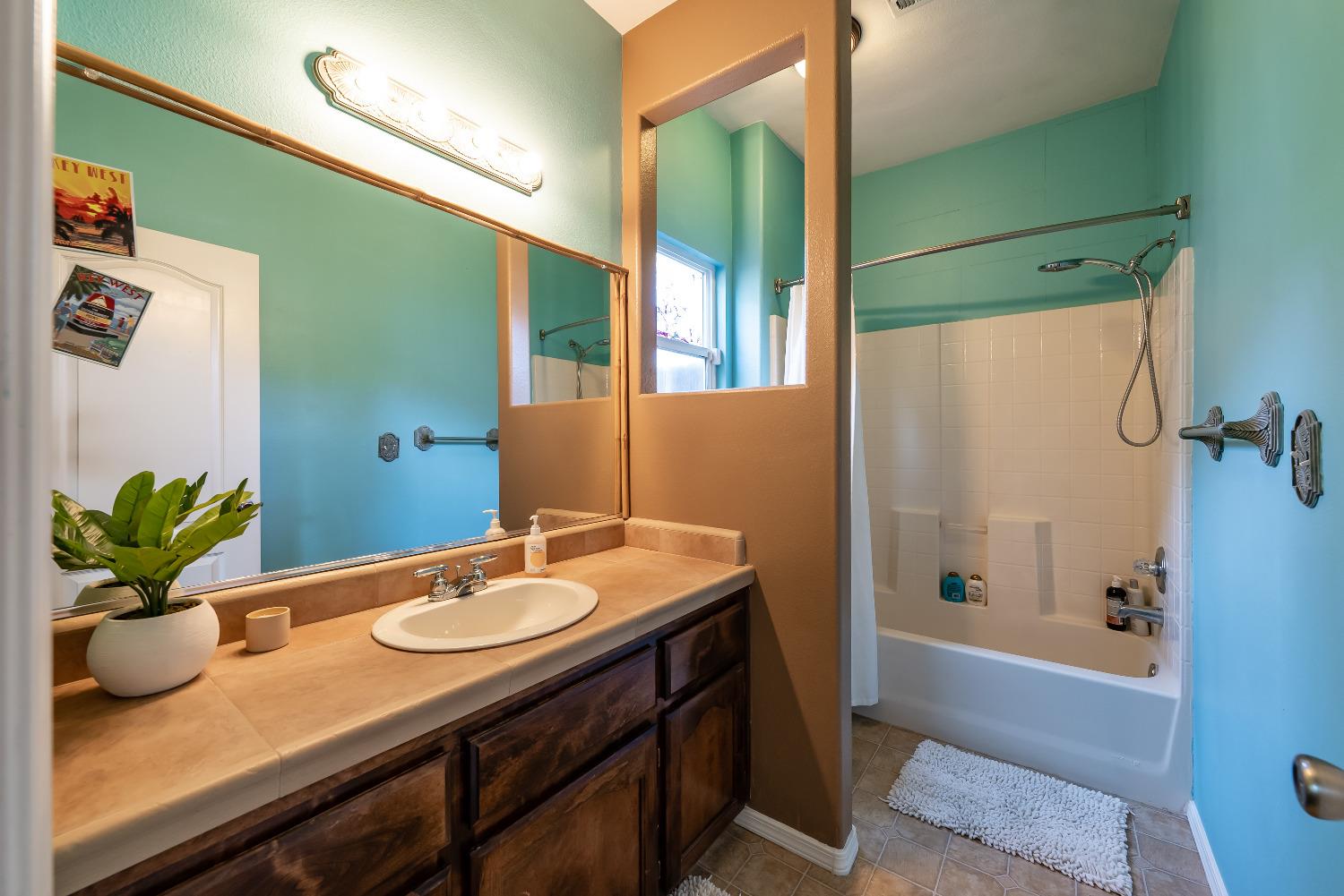 696 Crescent Lane Lemoore, CA 93245 - Photo 20 of 35 a bathroom with a granite countertop sink a mirror a potted plant and a bathtub