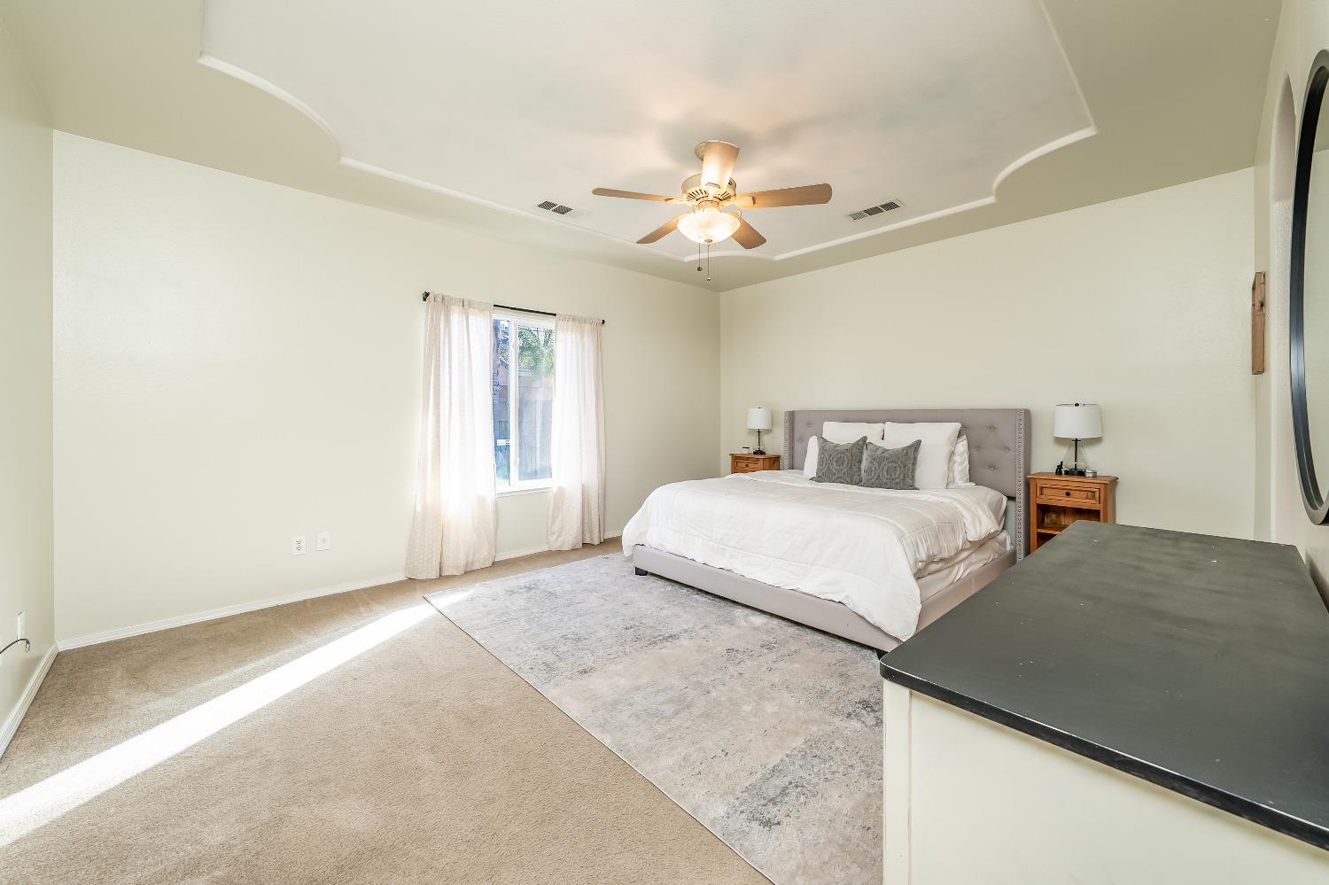 696 Crescent Lane Lemoore, CA 93245 - Photo 23 of 35 a bedroom with a large bed and a chandelier