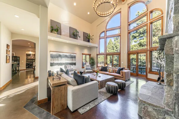 a living room with furniture two large windows and wooden floor