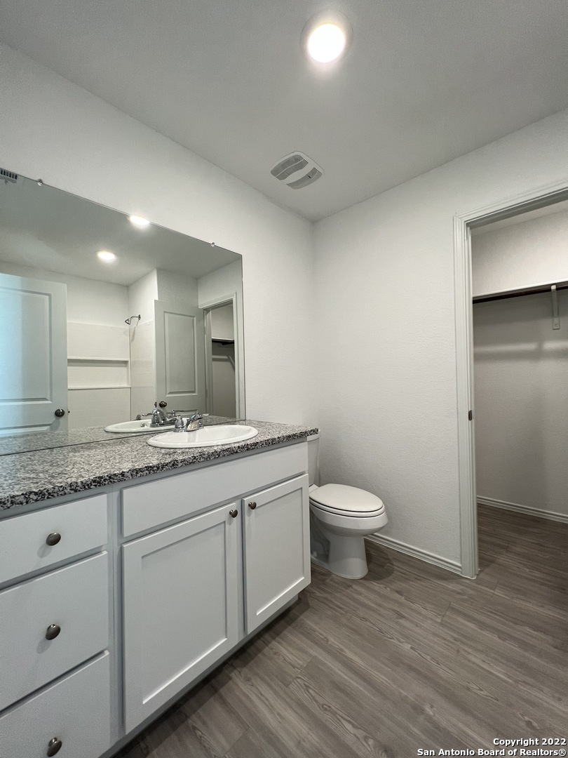 7314 Silos Ridge San Antonio, TX 78252 - Photo 31 of 45 a bathroom with a granite countertop toilet a sink and a mirror