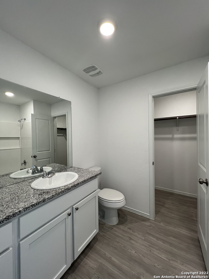 7314 Silos Ridge San Antonio, TX 78252 - Photo 35 of 45 a bathroom with a granite countertop sink a toilet and a mirror