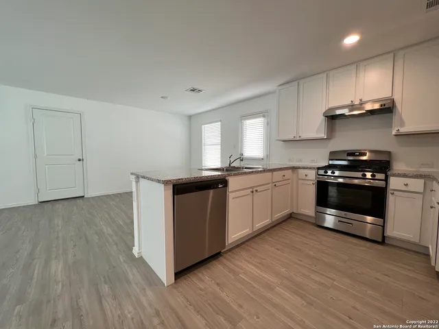 a kitchen with stainless steel appliances a sink and wooden floor