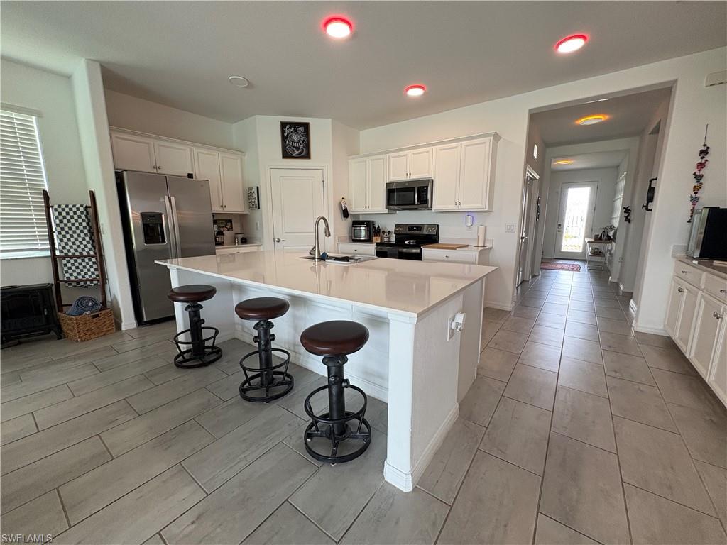 2458 Orchard Street Naples, FL 34120 - Photo 13 of 43 a kitchen with a sink a stove and chairs