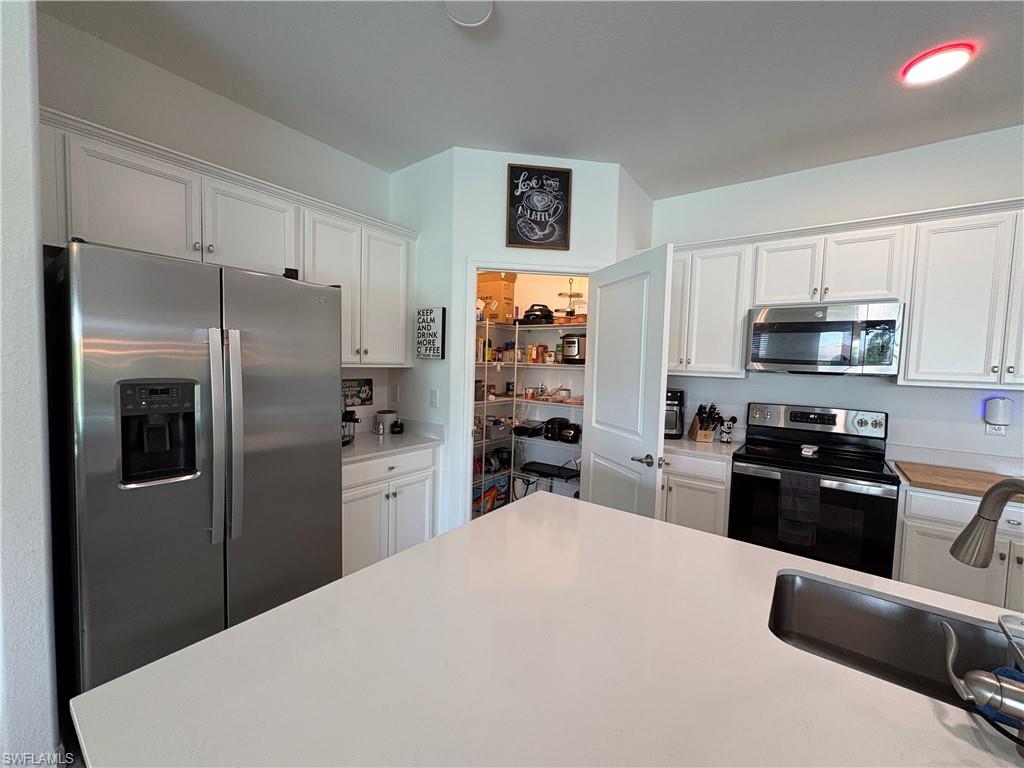 2458 Orchard Street Naples, FL 34120 - Photo 15 of 43 a kitchen with refrigerator a microwave a stove and cabinets