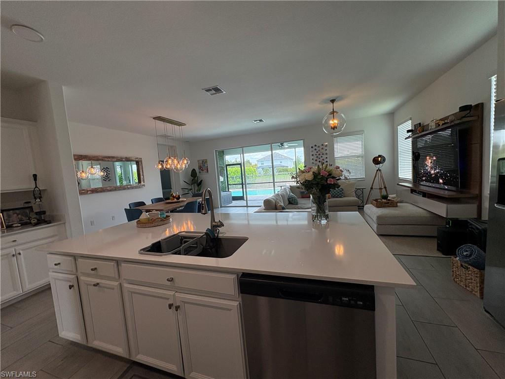 2458 Orchard Street Naples, FL 34120 - Photo 37 of 43 a kitchen with a sink dishwasher and white cabinets with wooden floor