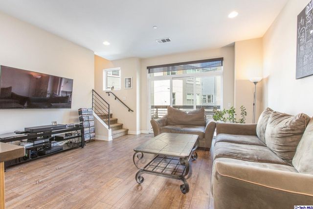 a living room with furniture a flat screen tv and a wooden floor