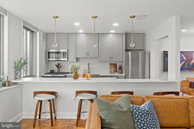 a kitchen with stainless steel appliances granite countertop a refrigerator a sink dishwasher a dining table and chairs with wooden floor