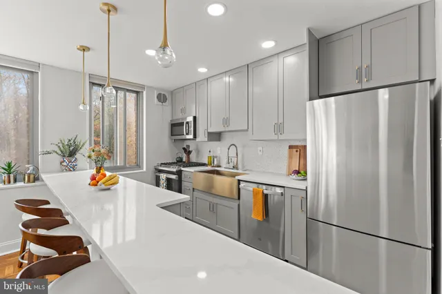 a kitchen with stainless steel appliances granite countertop a refrigerator a sink dishwasher a stove and a refrigerator with wooden floor