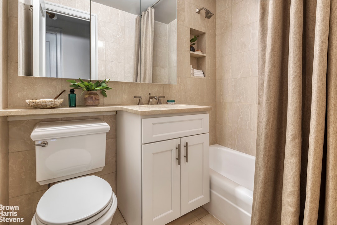 155 West 68th Street, Unit 28E Manhattan, NY 10023 - Photo 10 of 19 a bathroom with a toilet sink vanity and mirror