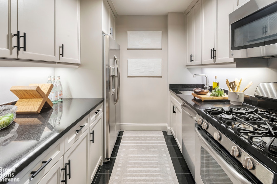 155 West 68th Street, Unit 28E Manhattan, NY 10023 - Photo 3 of 19 a kitchen with stainless steel appliances granite countertop a stove a refrigerator and a counter space