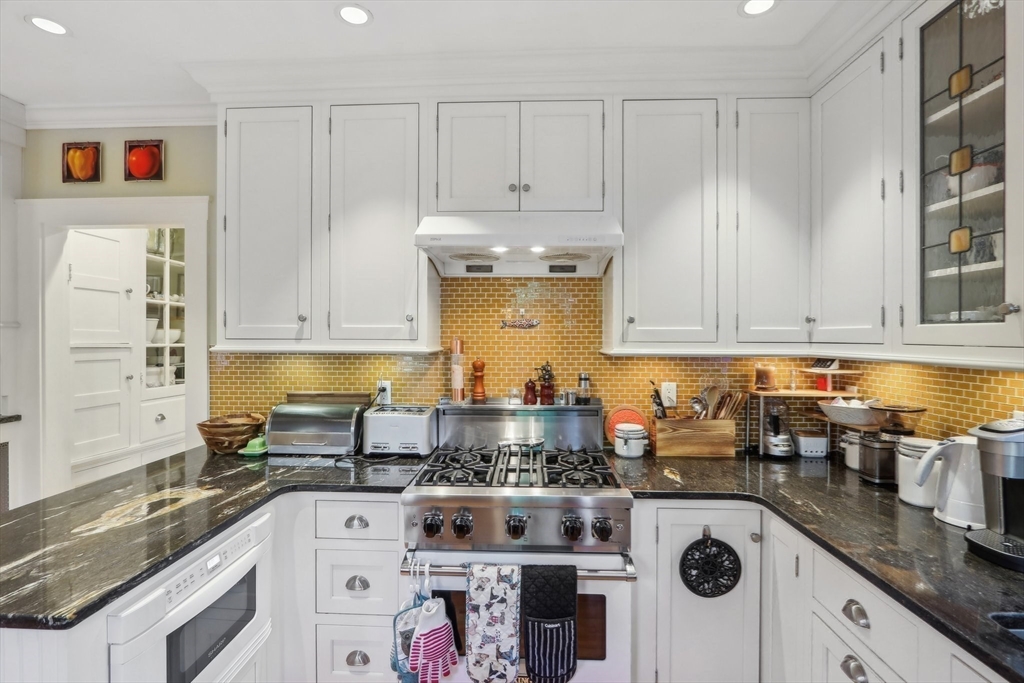 308 Prince Street Newton, MA 02465 - Photo 15 of 40 a kitchen with kitchen island granite countertop white cabinets and white appliances