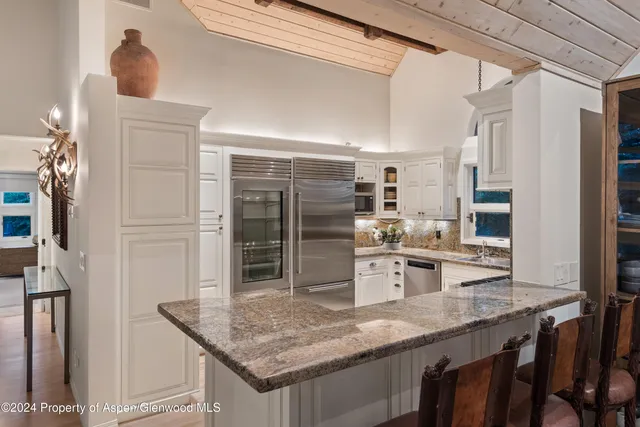 a kitchen with stainless steel appliances granite countertop a sink refrigerator and cabinets