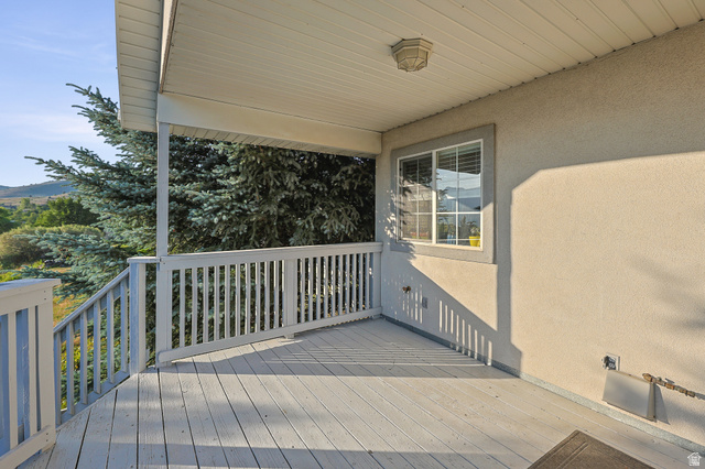4117 North Wolf Ridge Circle Eden, UT 84310 - Photo 53 of 63 Covered deck featuring a light-toned stucco exterior, white window trim, and painted railing