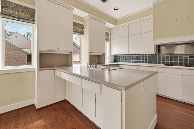 a kitchen with stainless steel appliances granite countertop a stove a sink and white cabinets with wooden floor