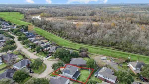 an aerial view of residential houses with outdoor space and trees