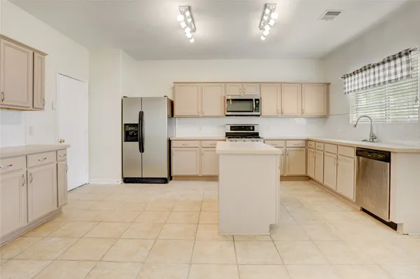 a kitchen with stainless steel appliances a sink stove refrigerator and cabinets