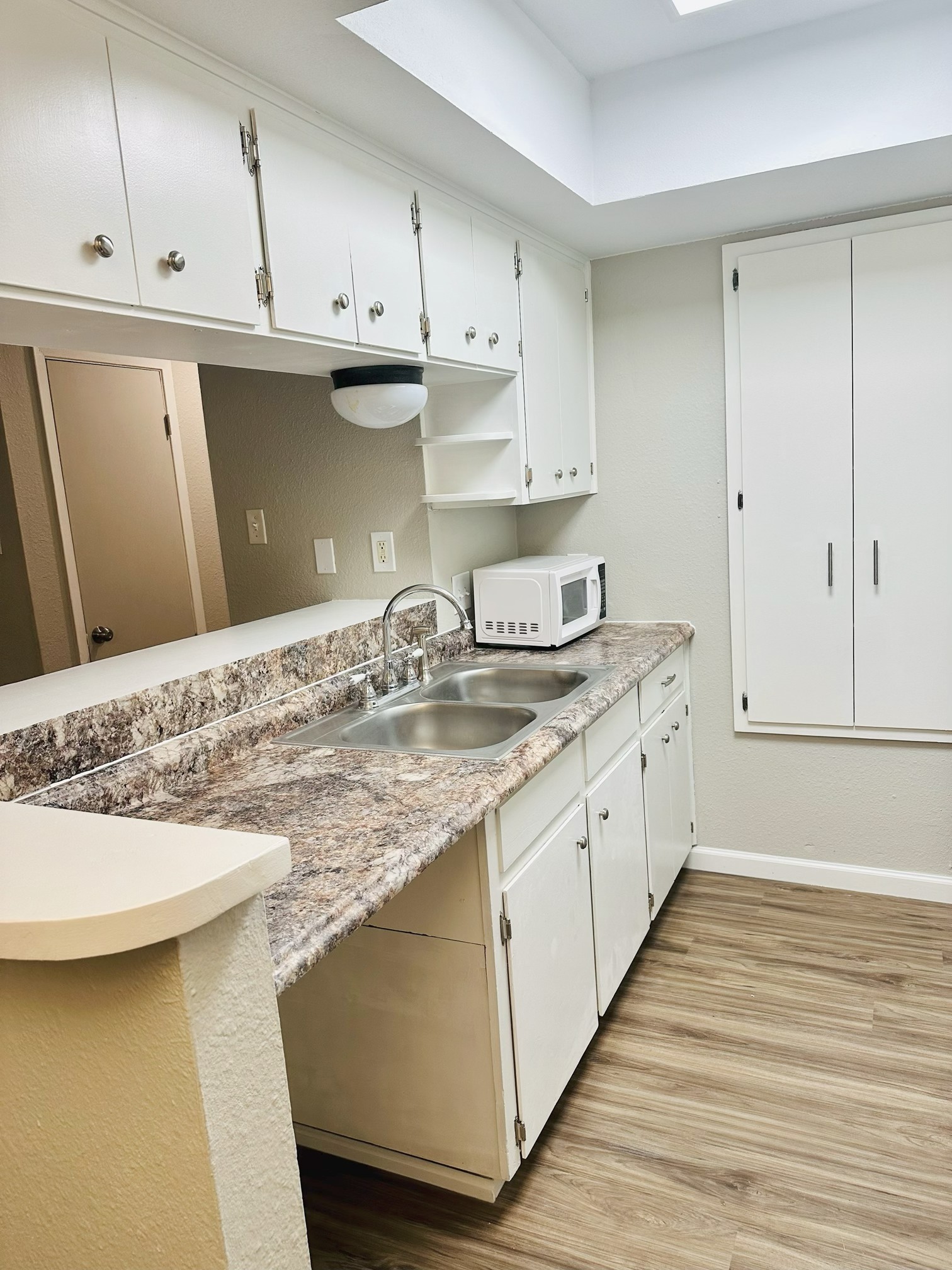 245 Mt Olive Road, Unit A & B Cedar Creek, TX 78612 - Photo 19 of 33 Unit A Kitchen featuring light countertops, light wood finished floors, white cabinets, and white microwave