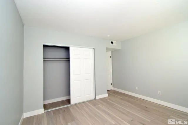 a view of an empty room with wooden floor and closet