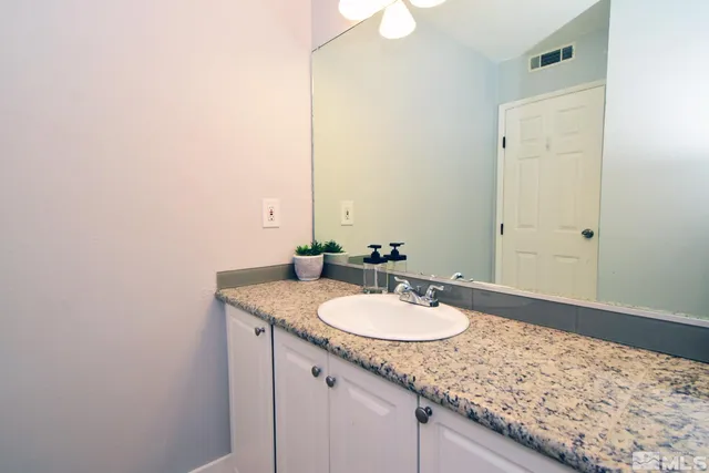 a bathroom with a granite countertop sink and a mirror
