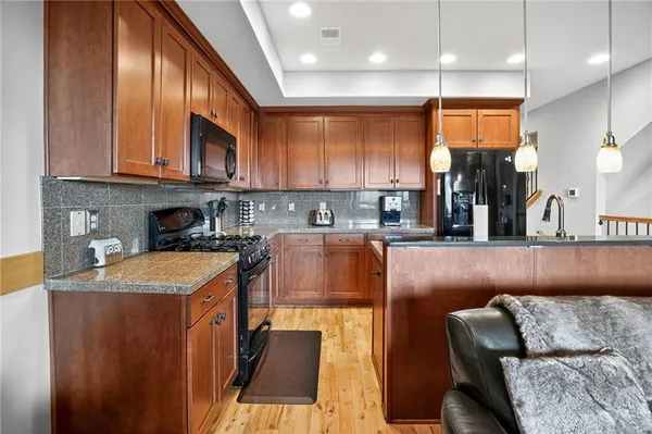 a kitchen with stainless steel appliances granite countertop a sink a stove top oven a chimney and a center island