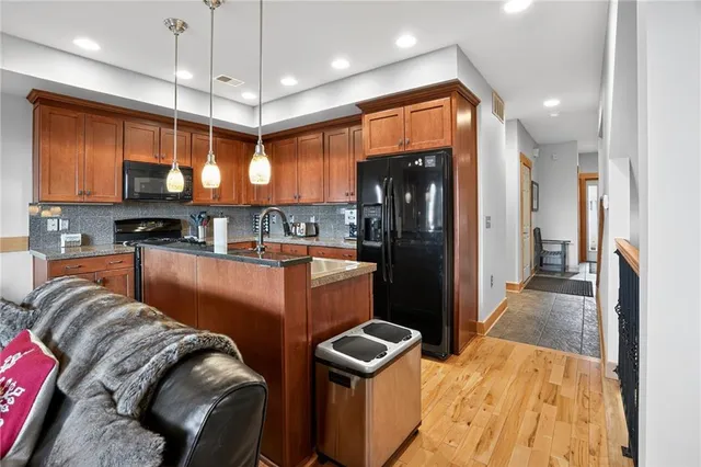 a kitchen with stainless steel appliances granite countertop a refrigerator a oven and a sink with wooden floor