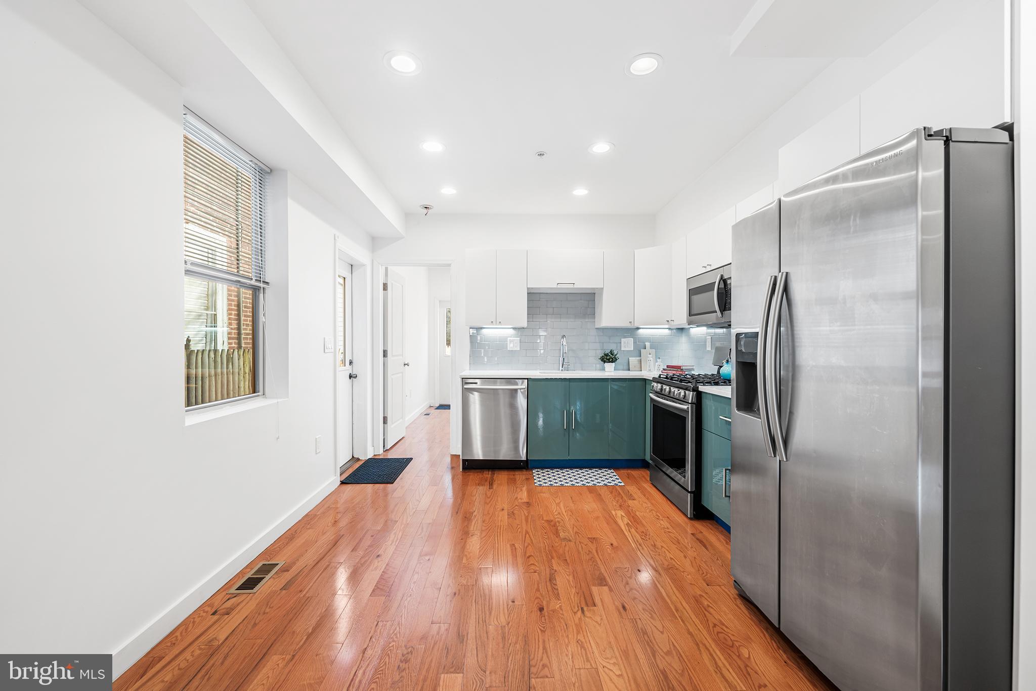 1346 South 46th Street Philadelphia, PA 19143 - Photo 11 of 32 a kitchen with stainless steel appliances granite countertop a refrigerator a sink a stove and white cabinets with wooden floor