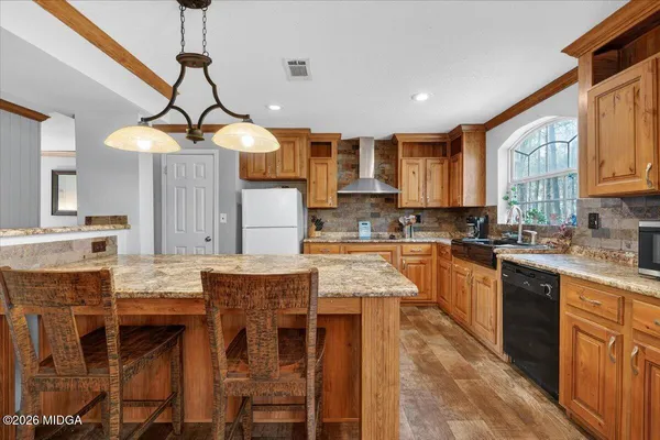 a kitchen with stainless steel appliances granite countertop a stove top oven a sink a dining table and chairs