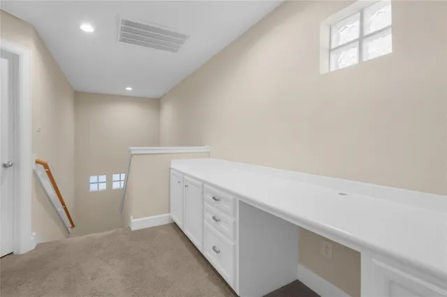 an empty room with chandelier fan and windows