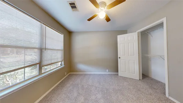 an empty room with a window and a fan