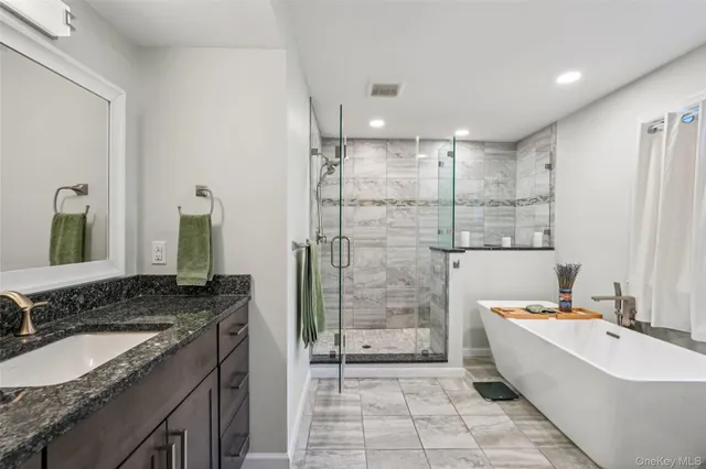 a bathroom with a granite countertop double vanity sink a mirror a bathtub and shower