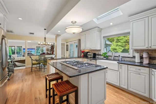 a kitchen with stainless steel appliances granite countertop a stove a sink dishwasher a dining table and chairs with wooden floor