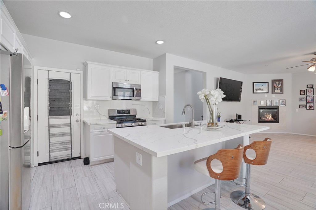 12179 Dewar Drive Riverside, CA 92505 - Photo 9 of 53 a kitchen with kitchen island granite countertop a stove a refrigerator a sink a dining table and chairs with wooden floor