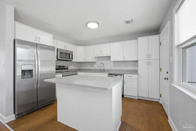 a kitchen with stainless steel appliances granite countertop a refrigerator a sink and white cabinets