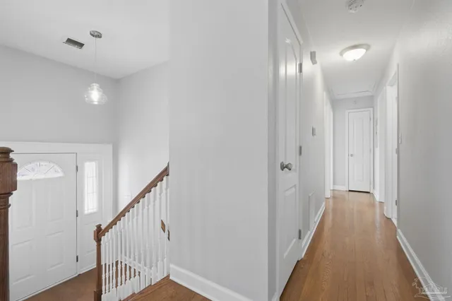 a view of a hallway with wooden floor and staircase