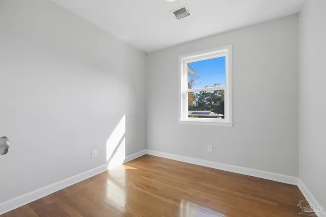 an empty room with wooden floor and window