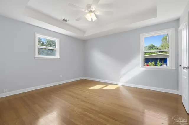 a view of an empty room with window and wooden floor