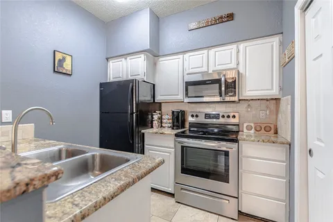 a kitchen with granite countertop a stove top oven and refrigerator
