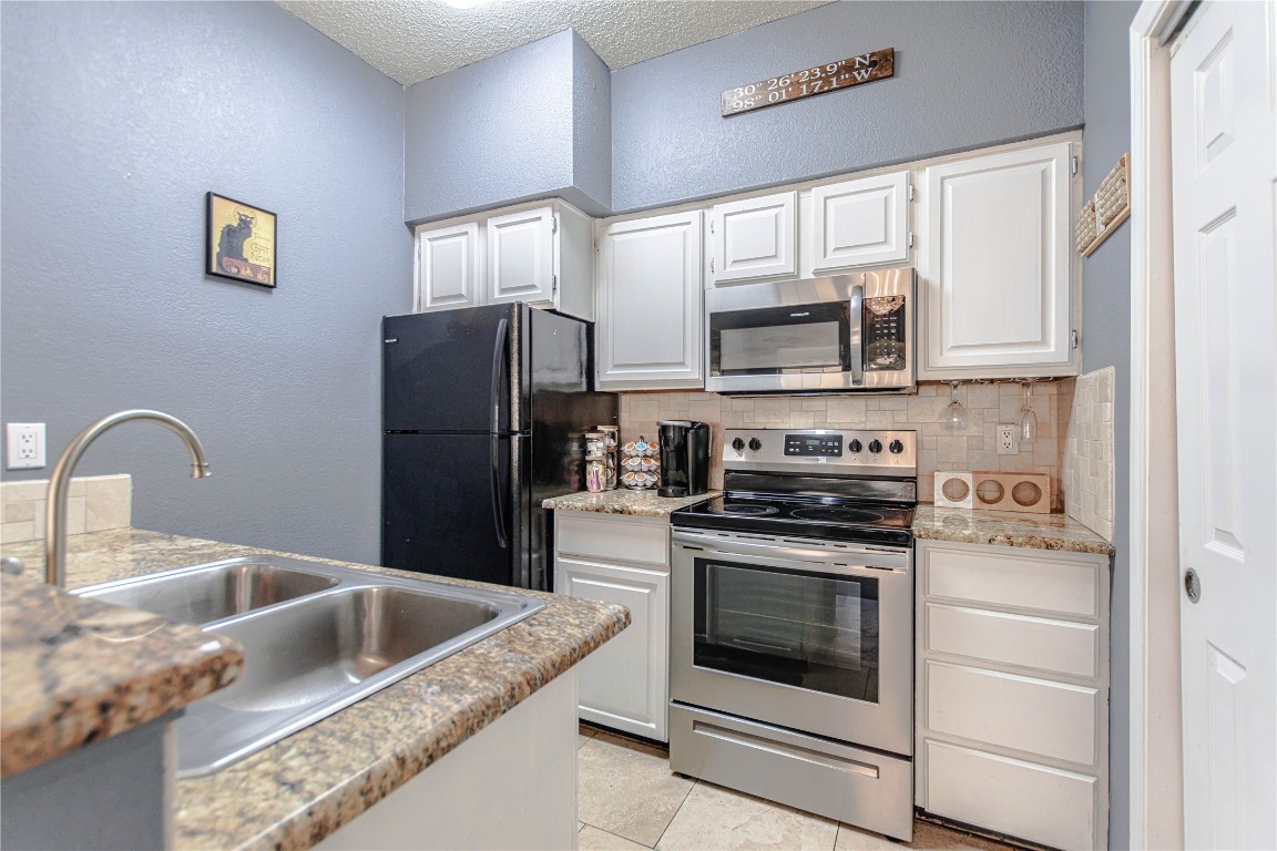 3404 American Drive, Unit 3226 Lago Vista, TX 78645 - Photo 14 of 40 a kitchen with granite countertop a stove top oven and refrigerator