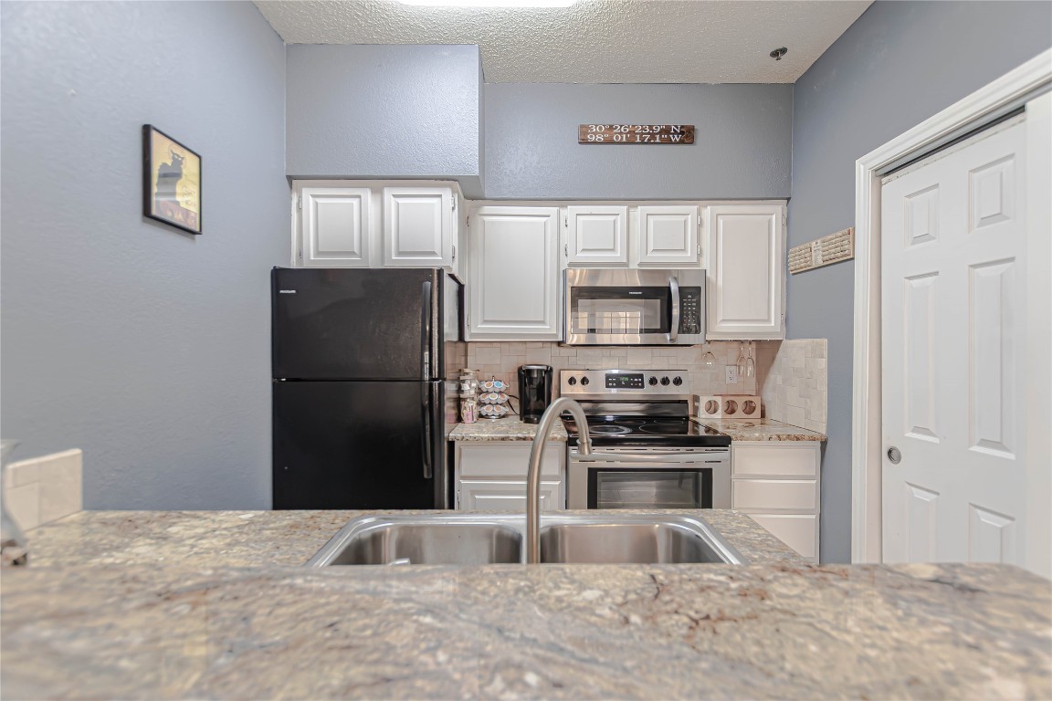 3404 American Drive, Unit 3226 Lago Vista, TX 78645 - Photo 16 of 40 a kitchen with granite countertop a refrigerator and a stove top oven