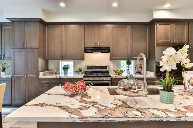 a kitchen with kitchen island granite countertop a sink cabinets and wooden floor